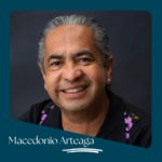 Portrait of a smiling man with graying hair wearing a black shirt with purple floral embroidery, turquoise ear studs, labeled "Macedonio Arteaga".