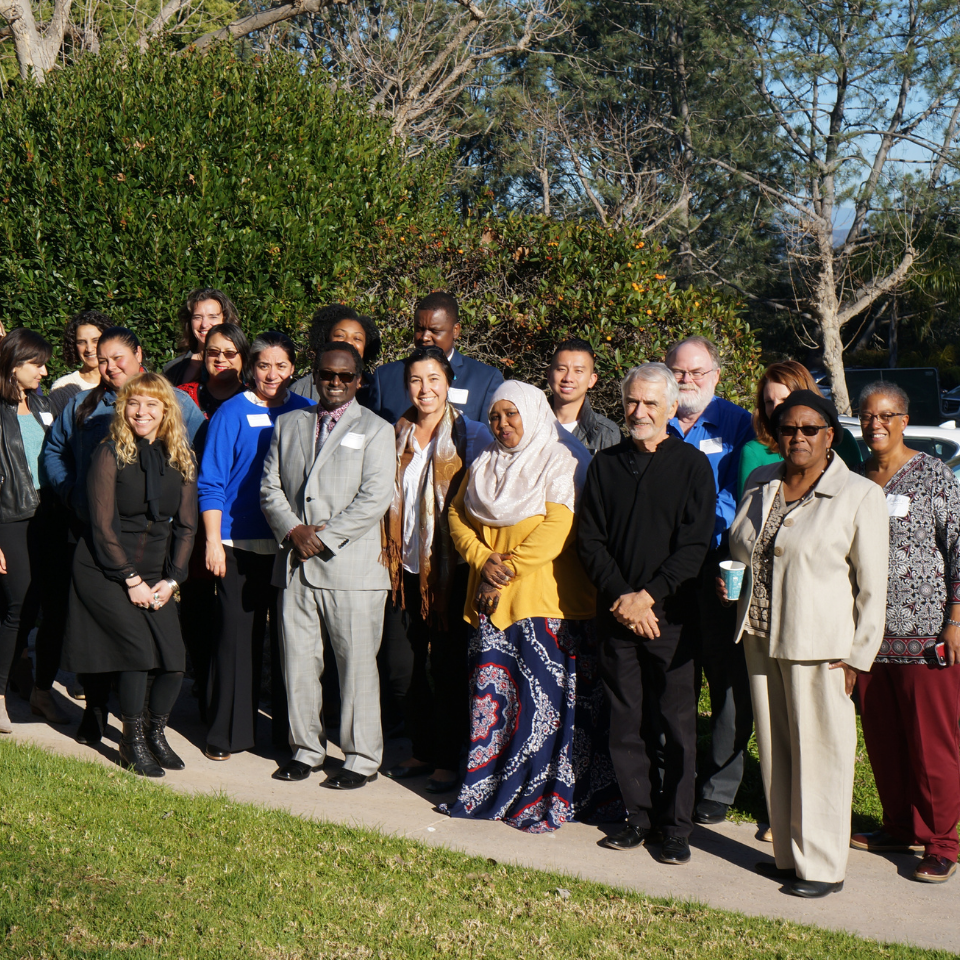 A large group of diverse individuals posing together in an outdoor setting